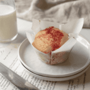 Strawberry Cream Cheese Muffin on a stack of white plates in a white parchment paper liner.