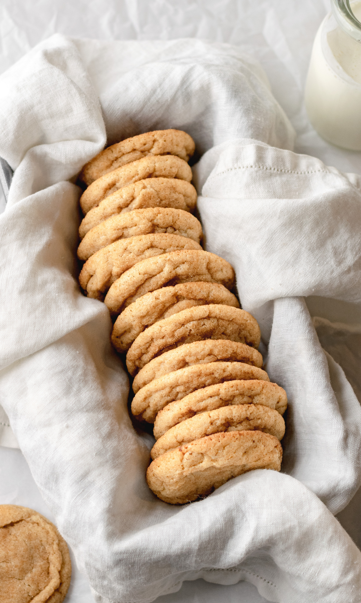 Snickerdoodle cookies lined up in a pan lined with a white cloth napkin.