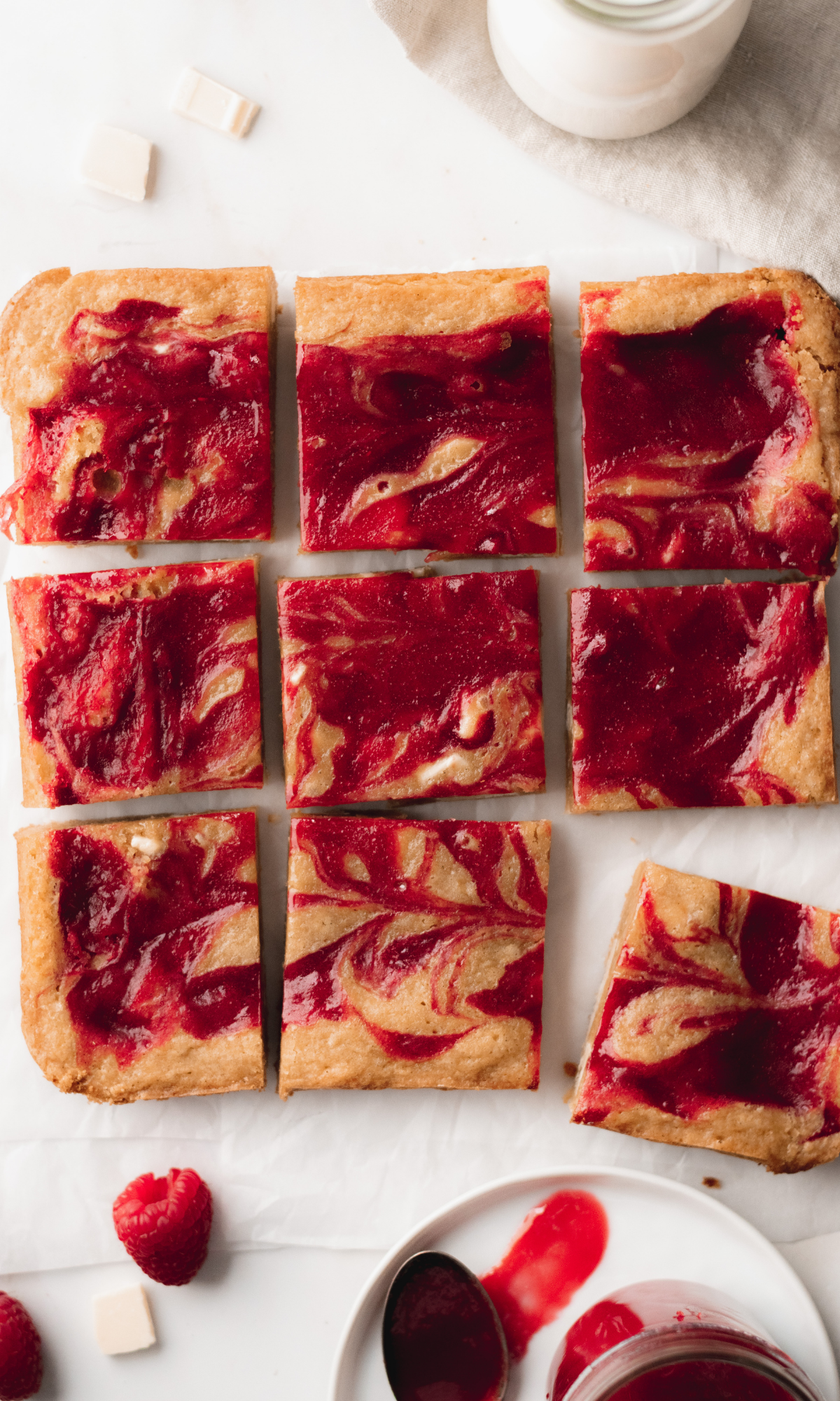An overhead shot of raspberry and white chocolate blondies cut into squares.