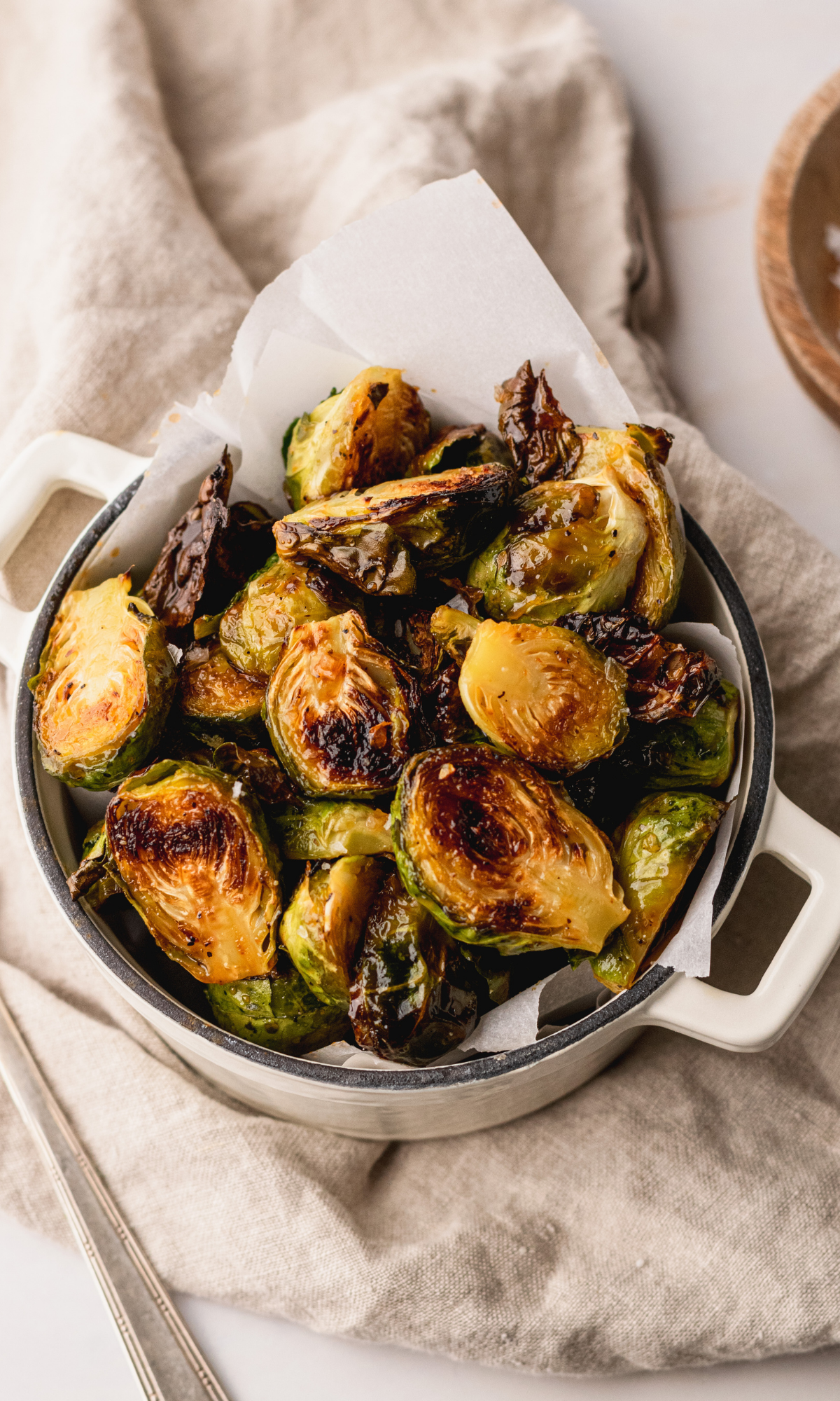 Honey Sriracha Brussels Sprouts in a small white dutch oven lined with white parchment paper.