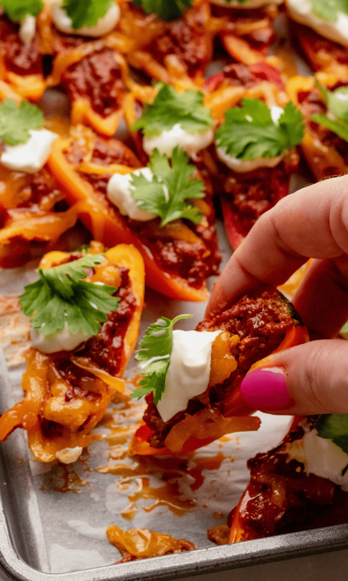 Mini Bell Pepper Nachos on a sheet pan with one getting picked up.