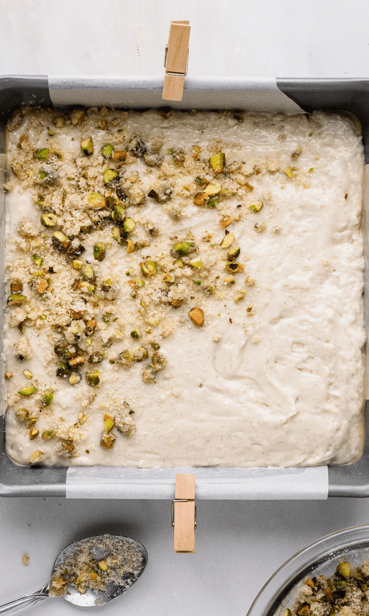 Overhead shot of pistachio crumble sprinkled on top of lemon pistachio cake batter.