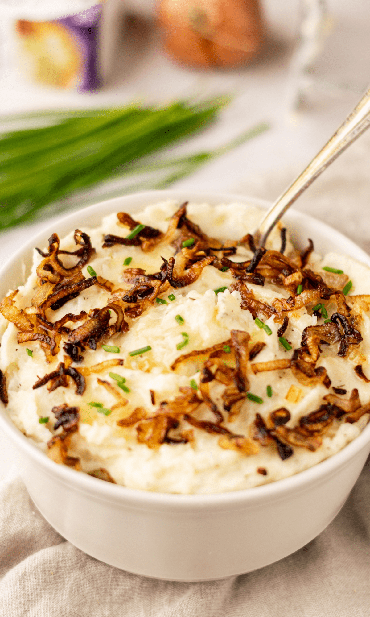 Boursin Mashed Potatoes with crispy shallots in a white bowl.