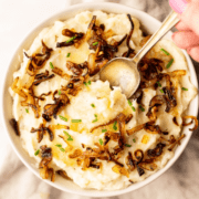 Overhead shot of Boursin Mashed Potatoes with crispy shallots in a white bowl.