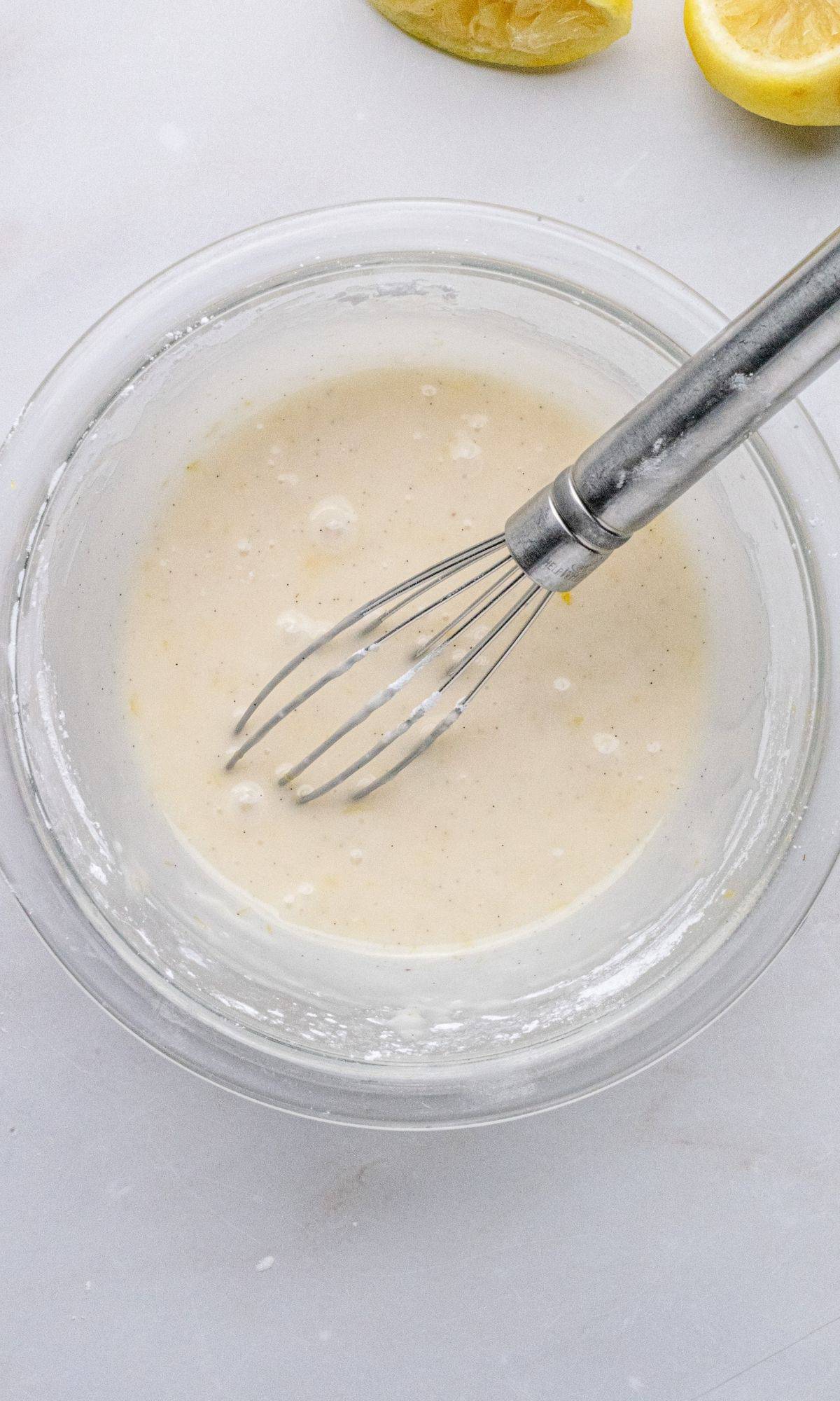 Lemon zest glaze in a bowl with a whisk.