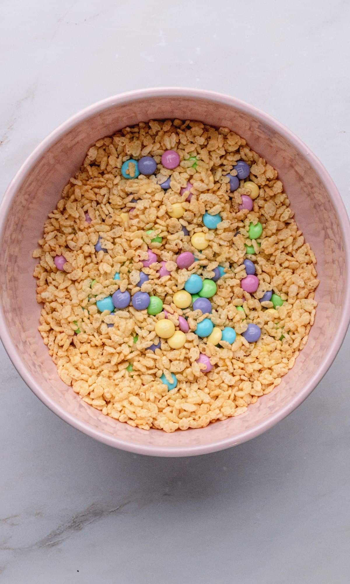 Overhead shot of rice krispies and M&Ms in a pink bowl.