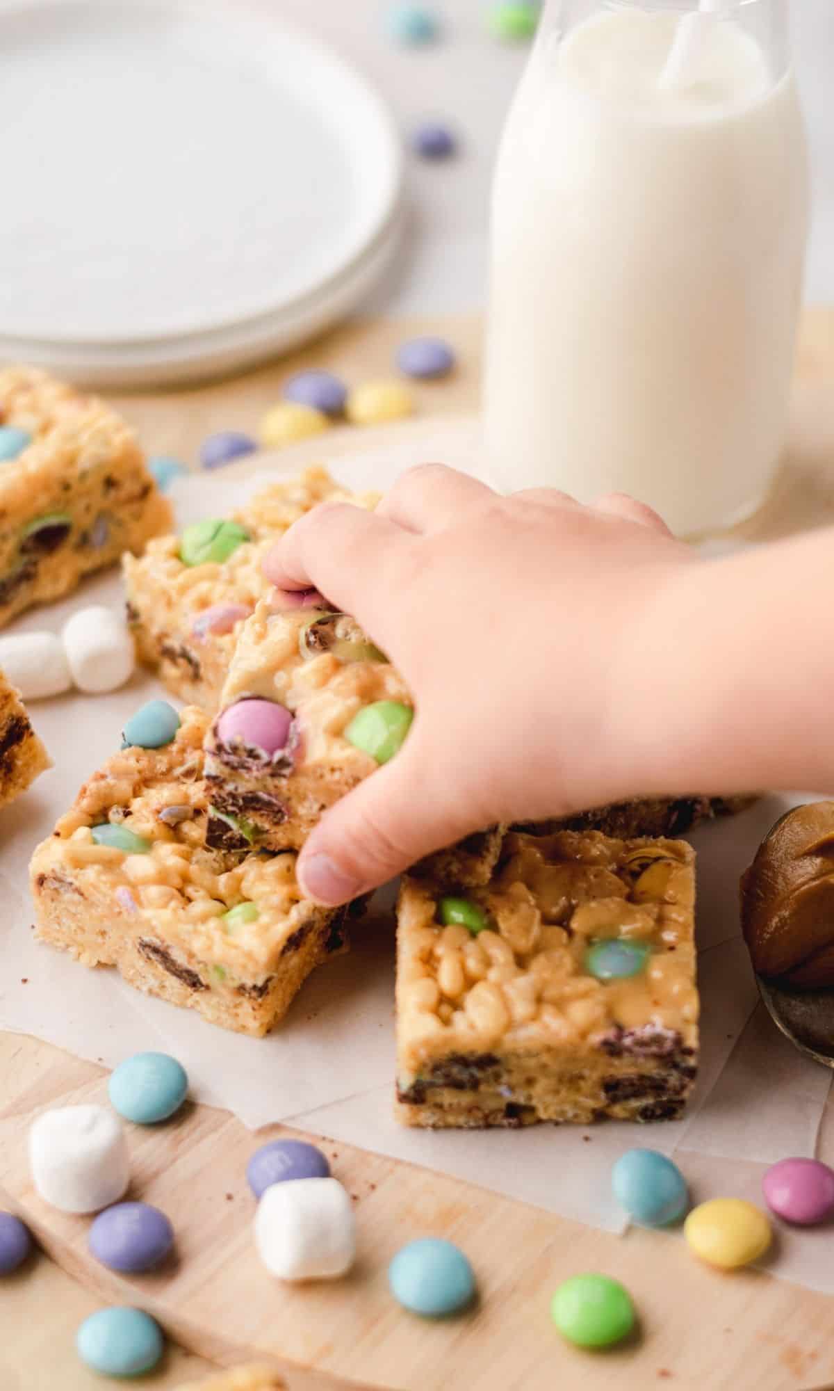 Peanut Butter Rice Krispies Treats with M&M's with a toddler hand grabbing one.
