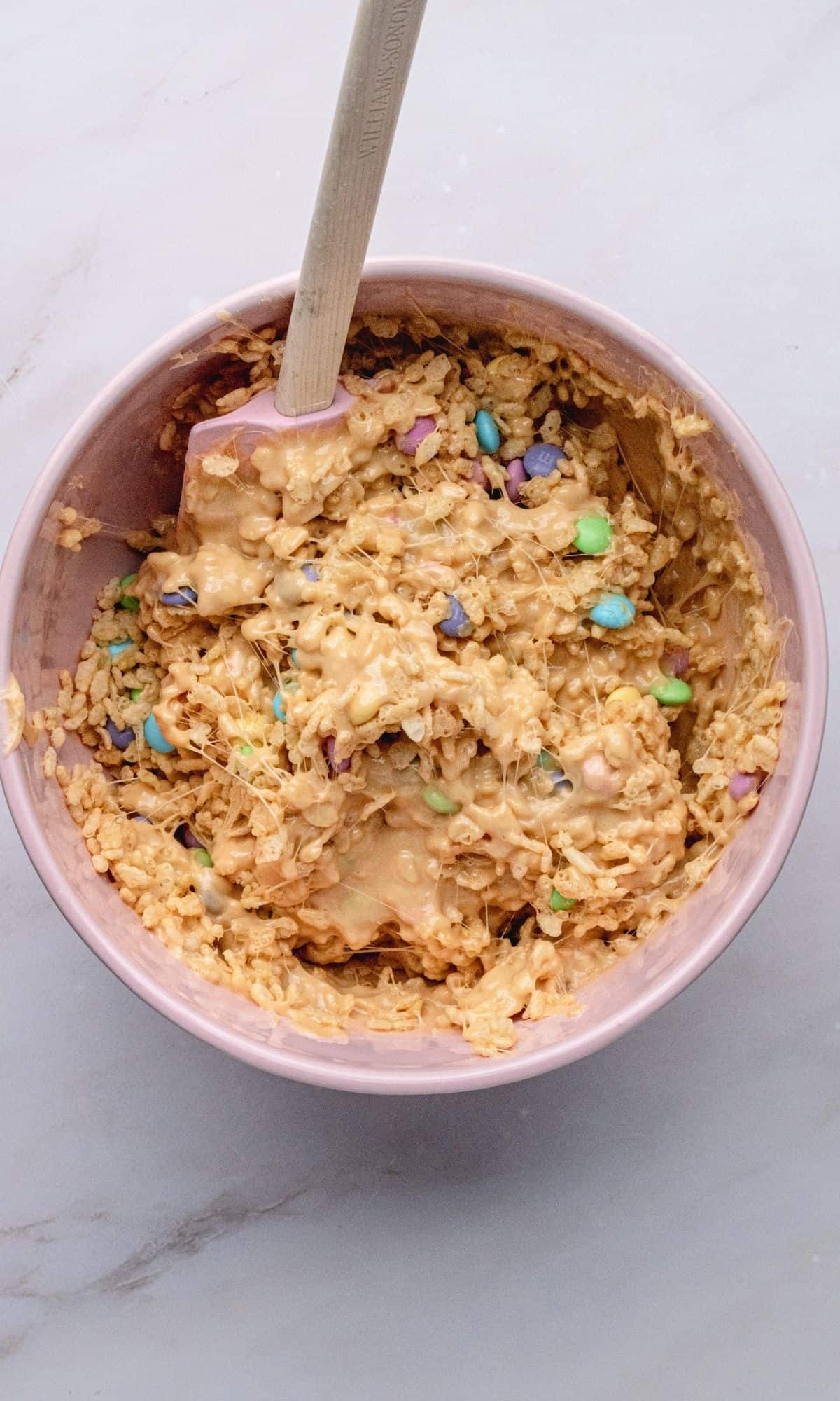 Overhead shot of peanut butter rice krispies with M&M's in mixing bowl.