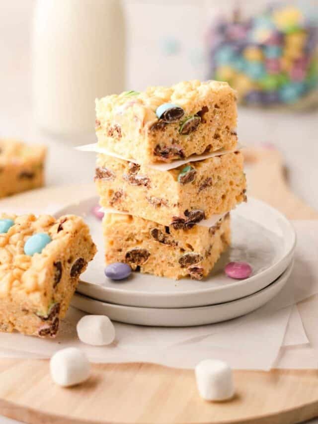 Peanut Butter Rice Krispies Treats with M&M's stacked on a white plate.