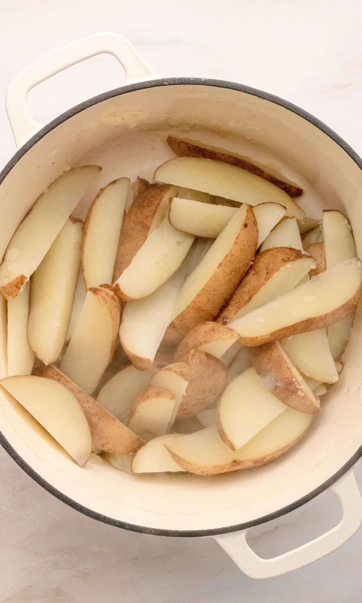 Hot potato wedges in a large white stock pot.