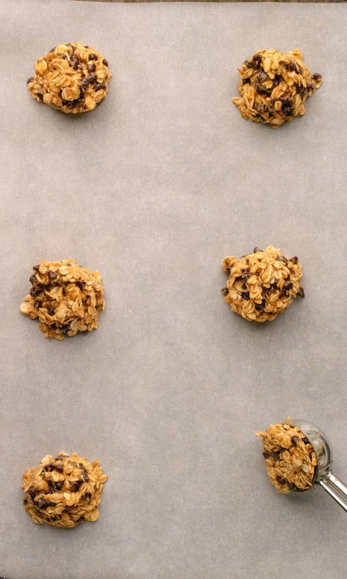 Peanut butter chocolate chip cookie dough being placed on a baking sheet.