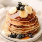 A stack of banana blueberry buttermilk pancakes on a white plate.