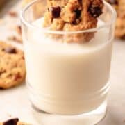 Oatmeal cookie getting dunked into a glass of milk.
