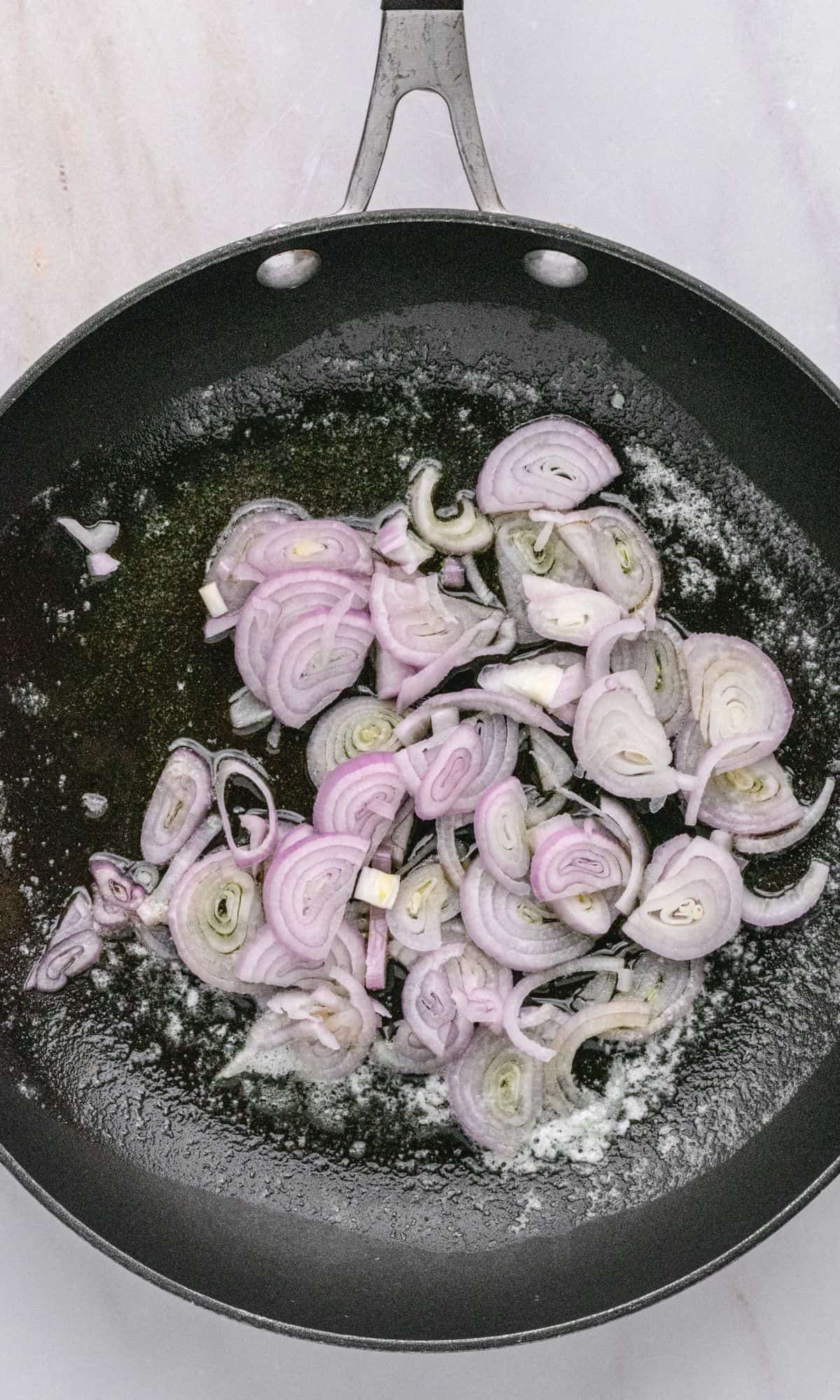 Crispy shallot preparation in small frying pan.