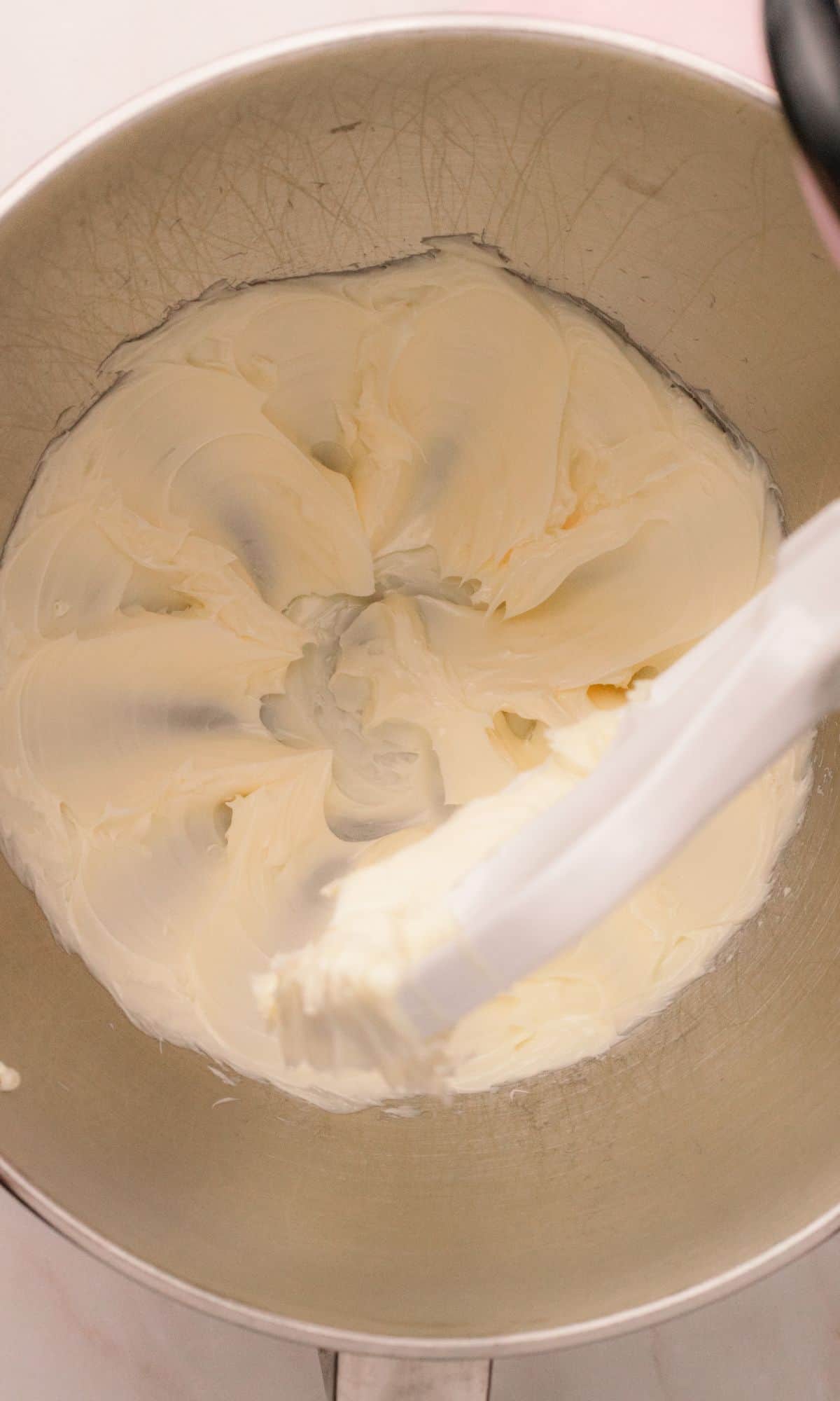 Whipped butter in the bowl of a stand mixer for strawberry buttercream frosting.