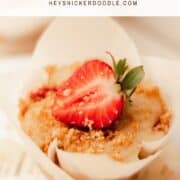 A strawberry cheesecake muffin in a white parchment paper liner topped with a strawberry.
