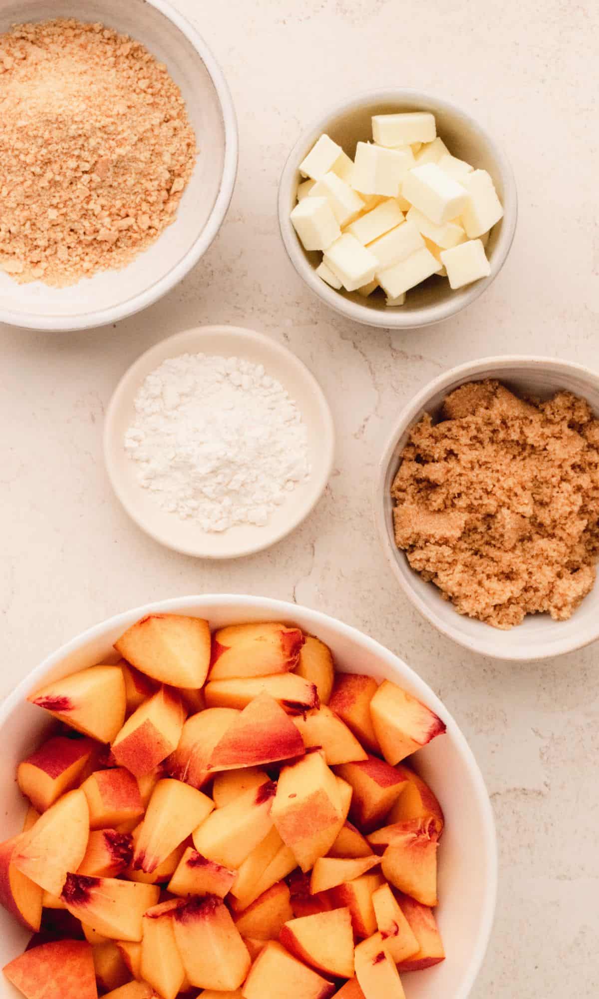 Peach crisp ingredients in varying bowl shapes and sizes.