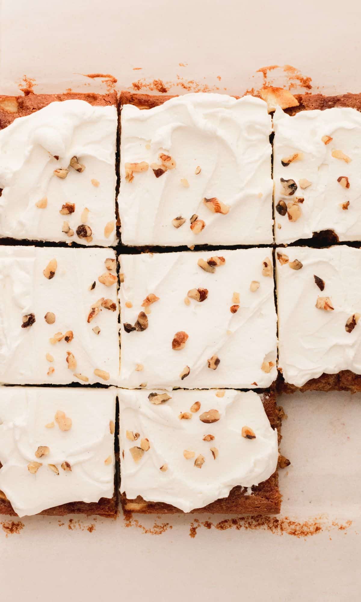 Cut sour cream apple bars topped with whipped cream and walnuts.