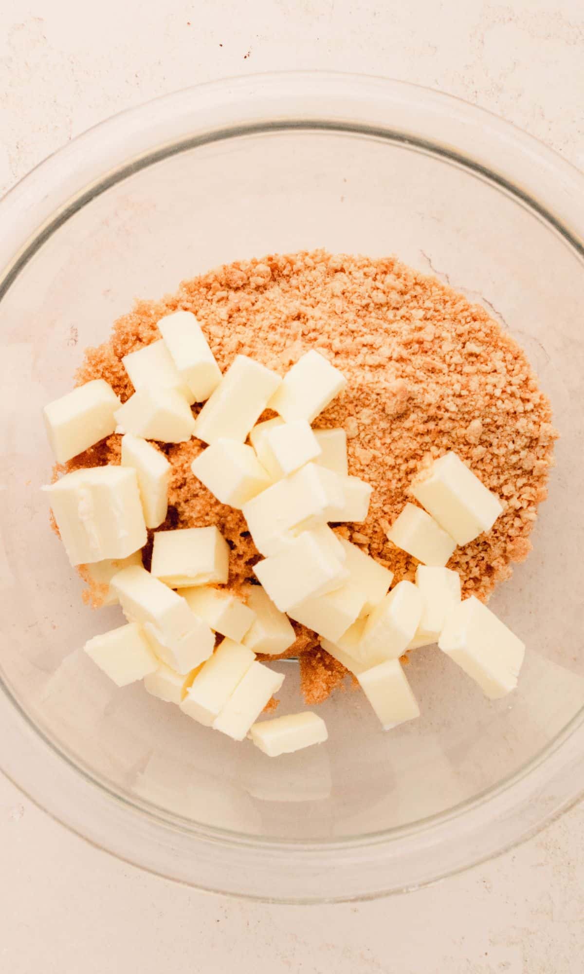 Butter, brown sugar and graham cracker crumbs in a glass bowl.