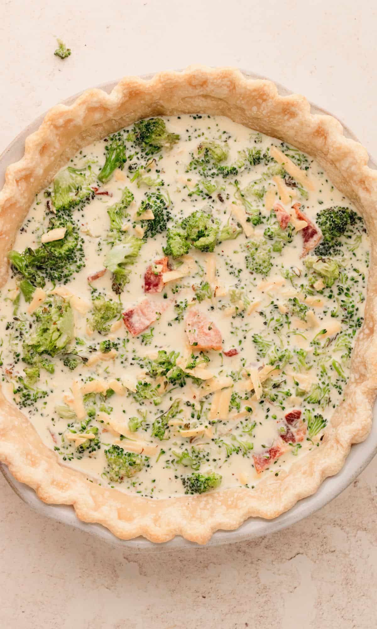 Unbaked filled pie crust with quiche filling.