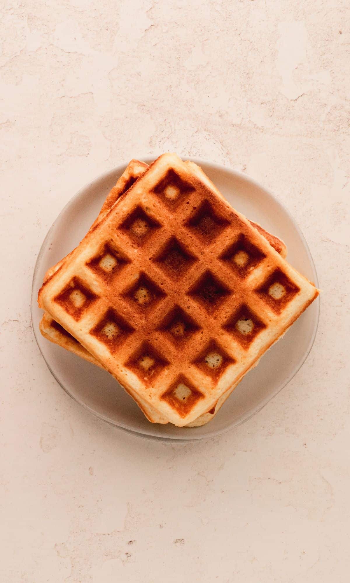 Belgian waffles stacked on a white plate.