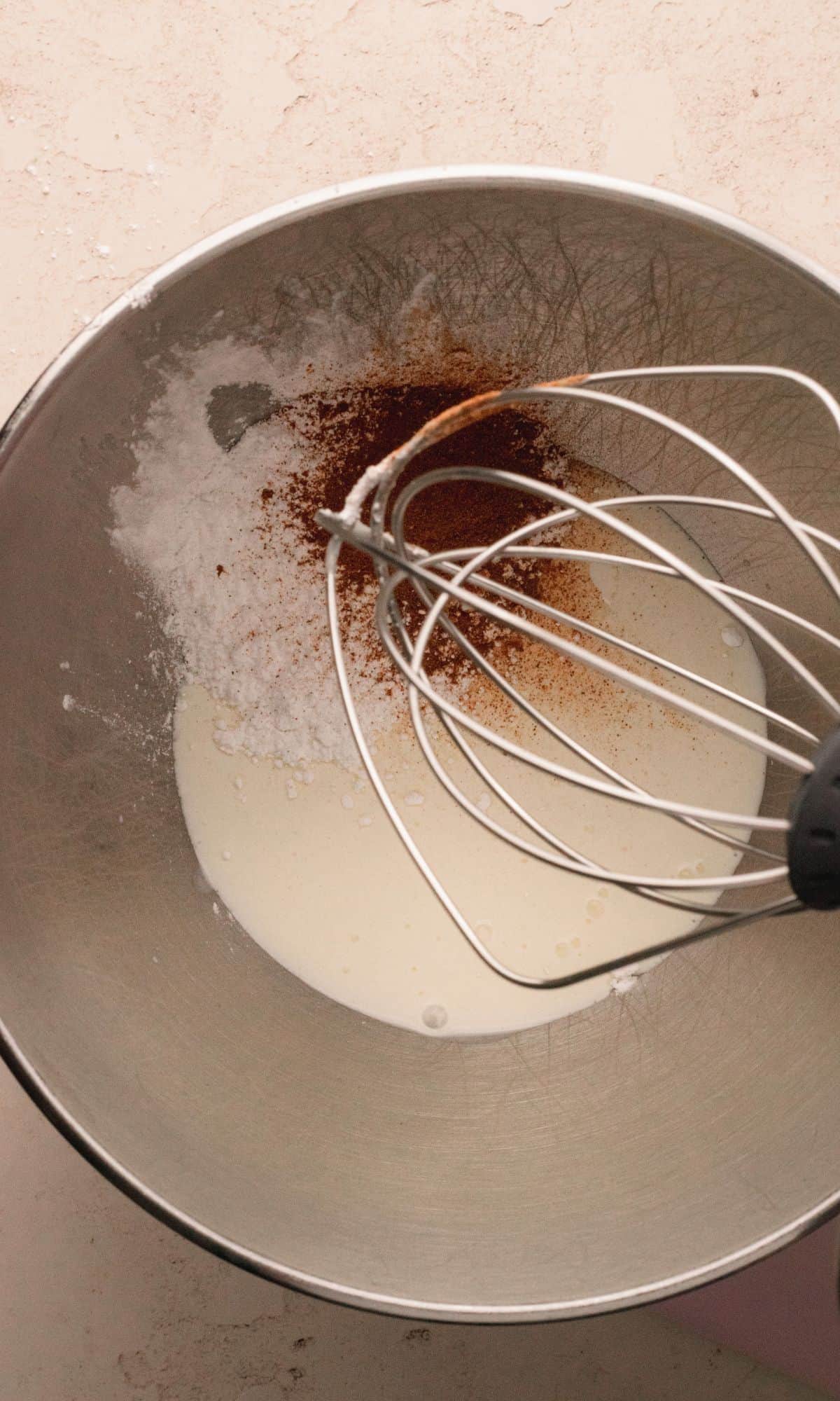 Spiced whipped cream ingredients in a metal bowl.
