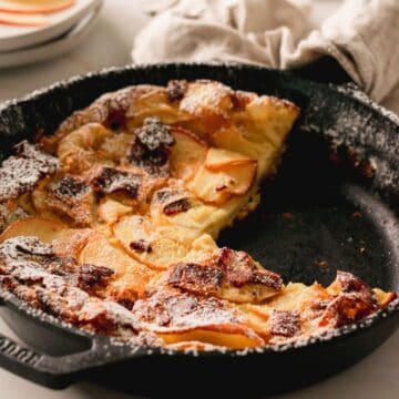 Bacon apple dutch baby preparation in a cast iron skillet.