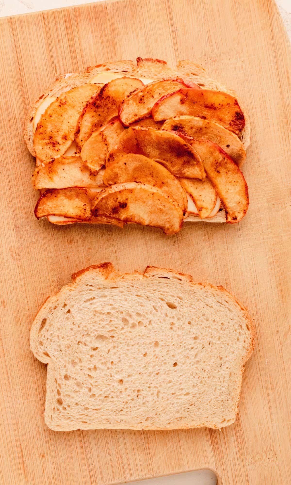 Roasted apple and chicken panini preparation on a cutting board.
