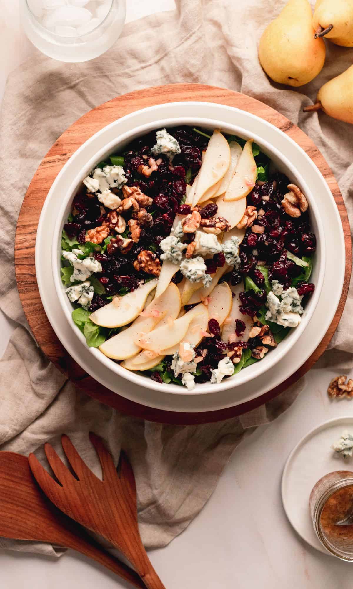 Pear, blue cheese, and toasted walnut salad in a white bowl.