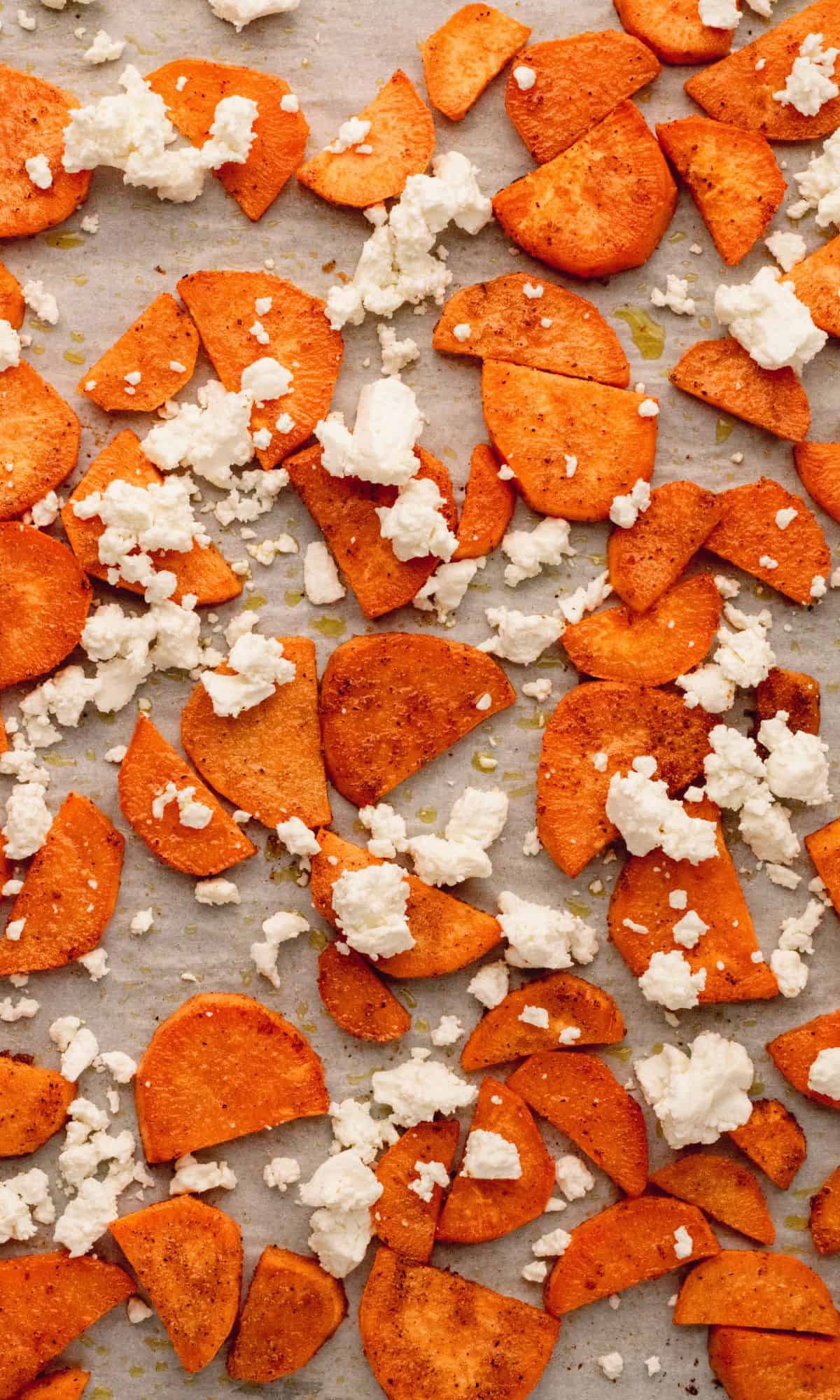 Sliced sweet potatoes and goat cheese on a baking sheet.