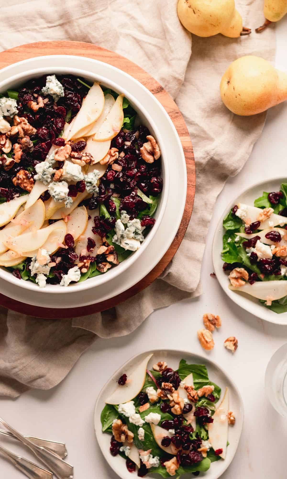 Pear, blue cheese, and toasted walnut salad in a white bowl.