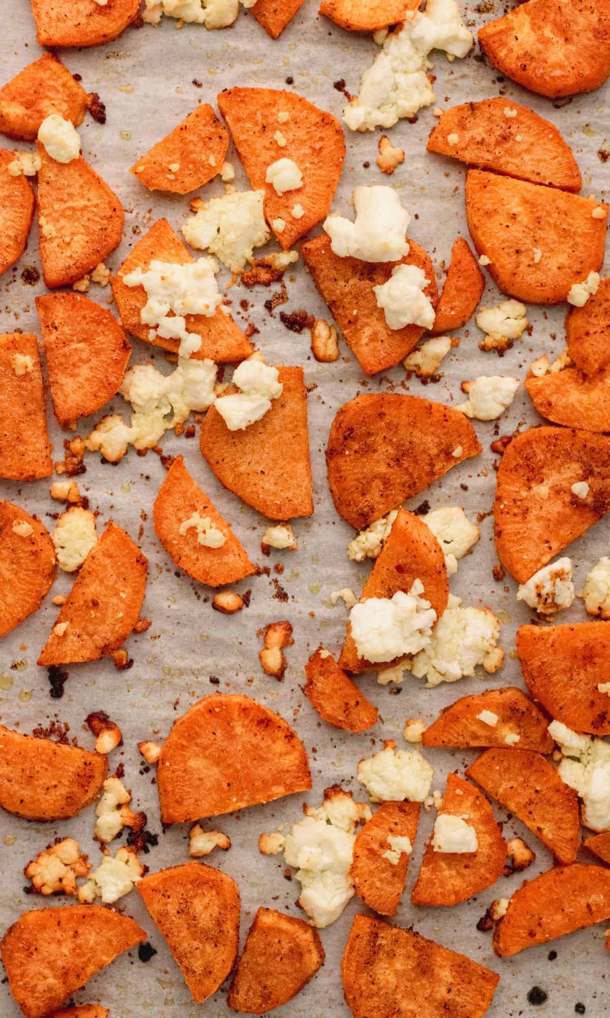 Sliced sweet potatoes and goat cheese on baking sheet.
