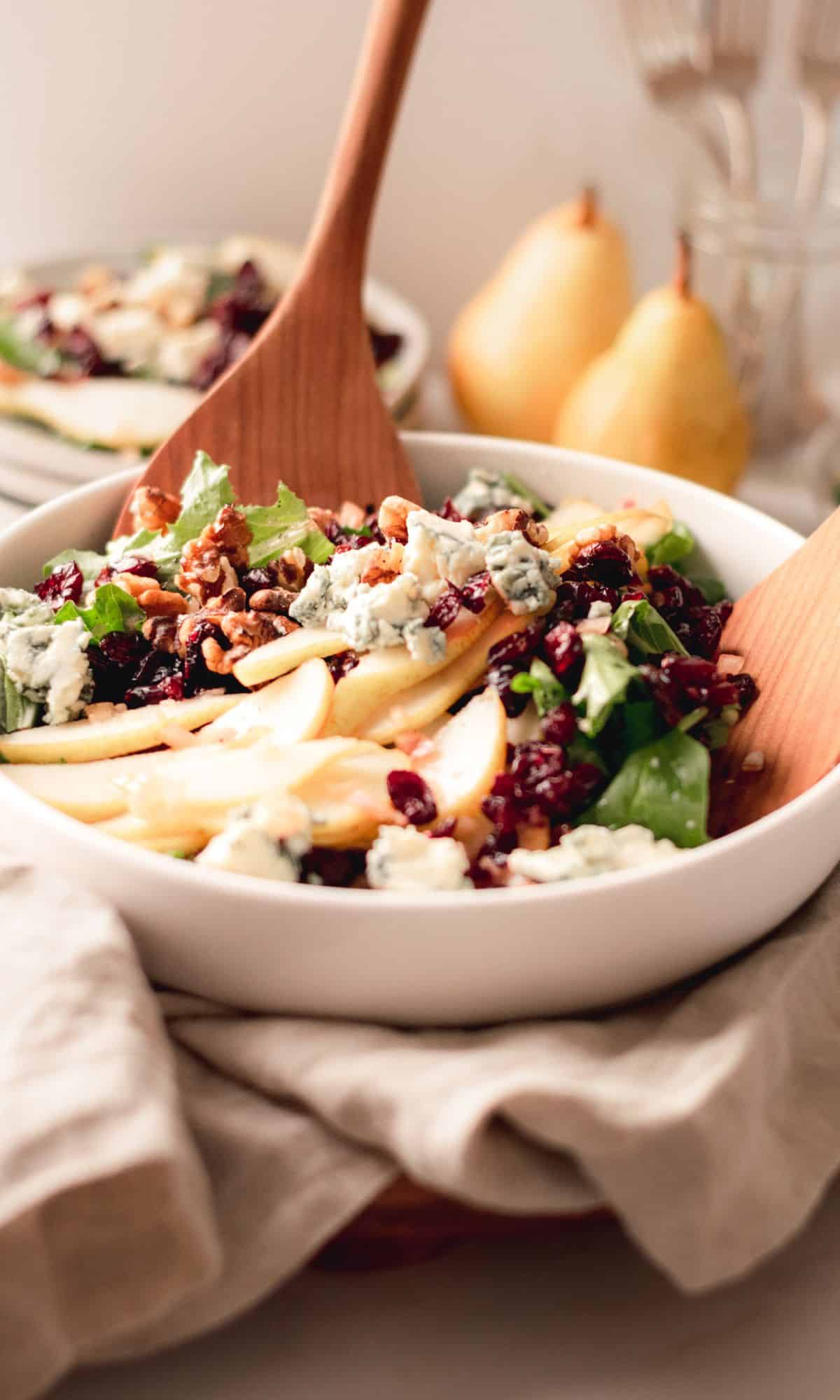 Pear, blue cheese, and toasted walnut salad in a white bowl.