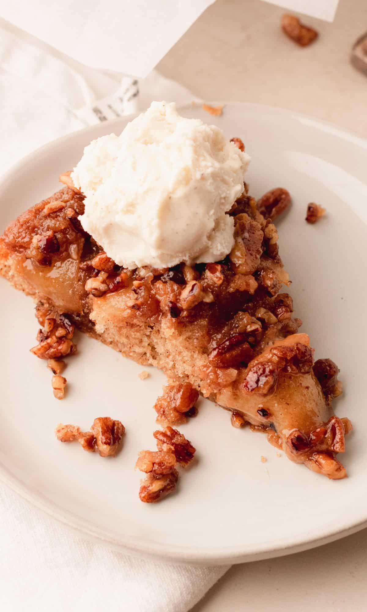 A slice of caramel pecan apple spice upside down cake topped with ice cream.