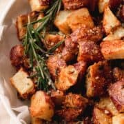 Roasted red potatoes with rosemary in a white bowl.