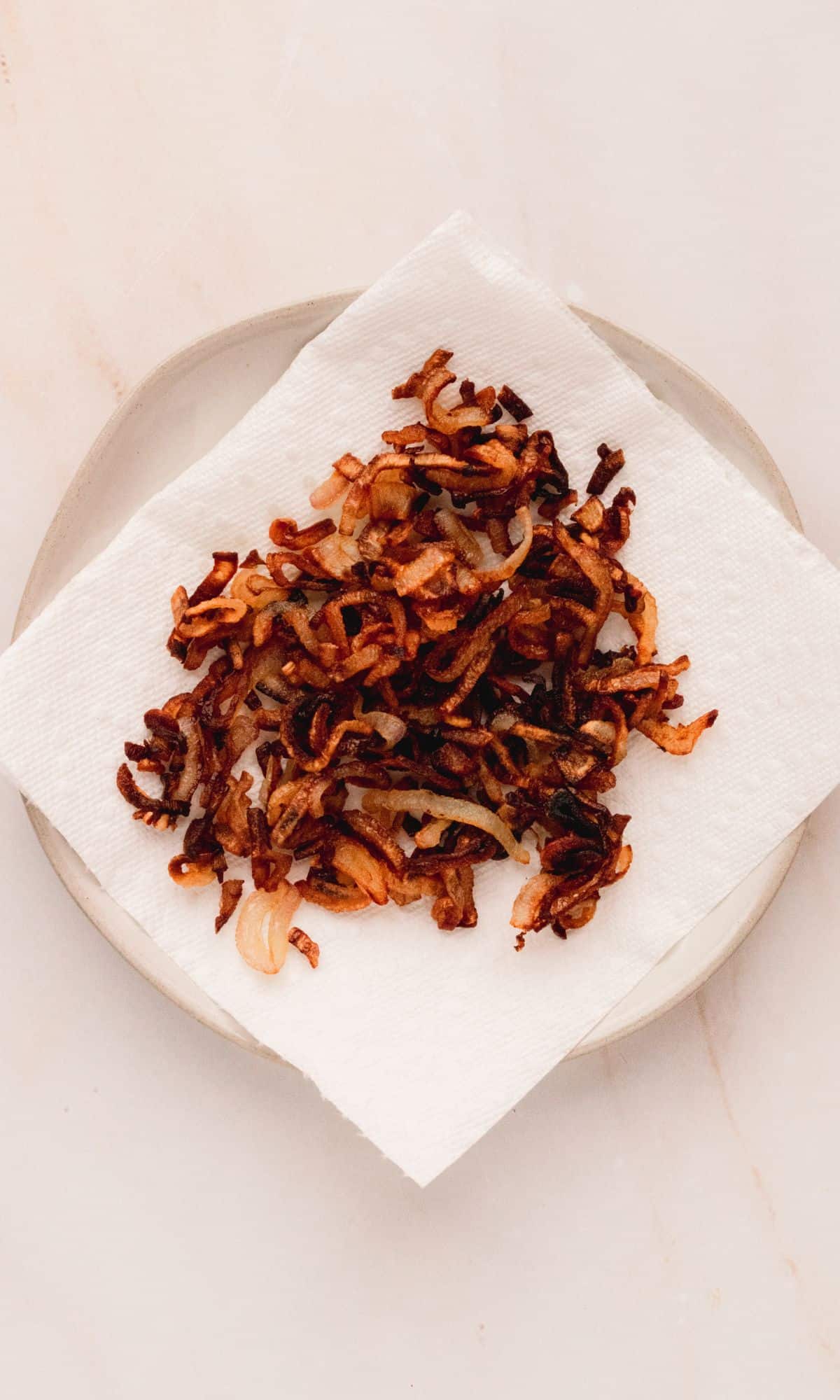 Crispy shallots on a paper towel lined plate.