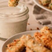 A zucchini fry getting dipped in a jar of ranch dressing.
