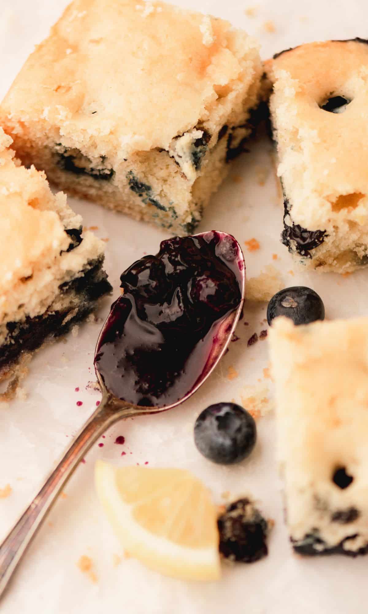 Buttermilk cake with blueberries and a spoon with blueberry compote on it.