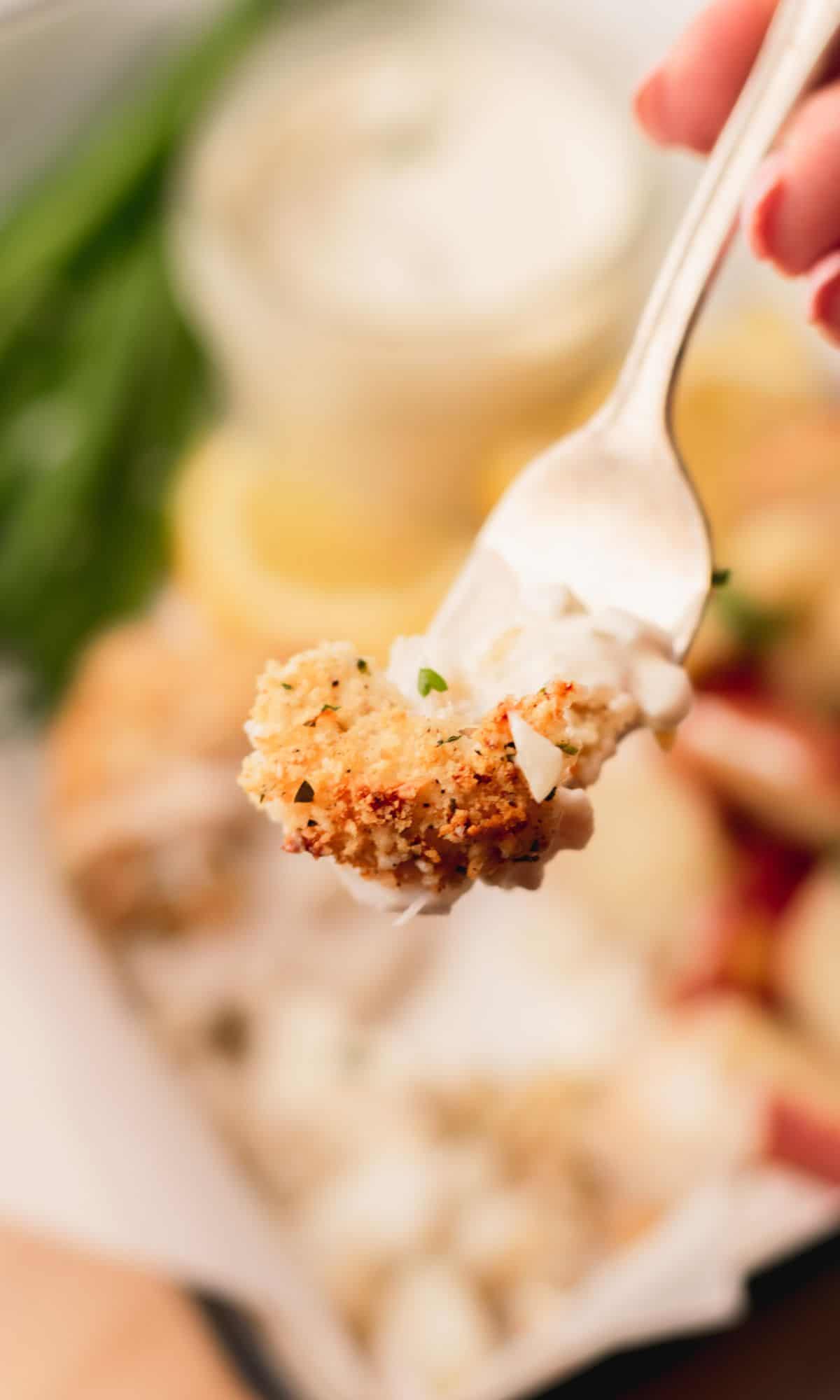 A bite of parmesan panko baked cod on a fork.