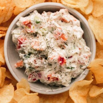 A bowl of smoked salmon dip with potato chips surrounding it.