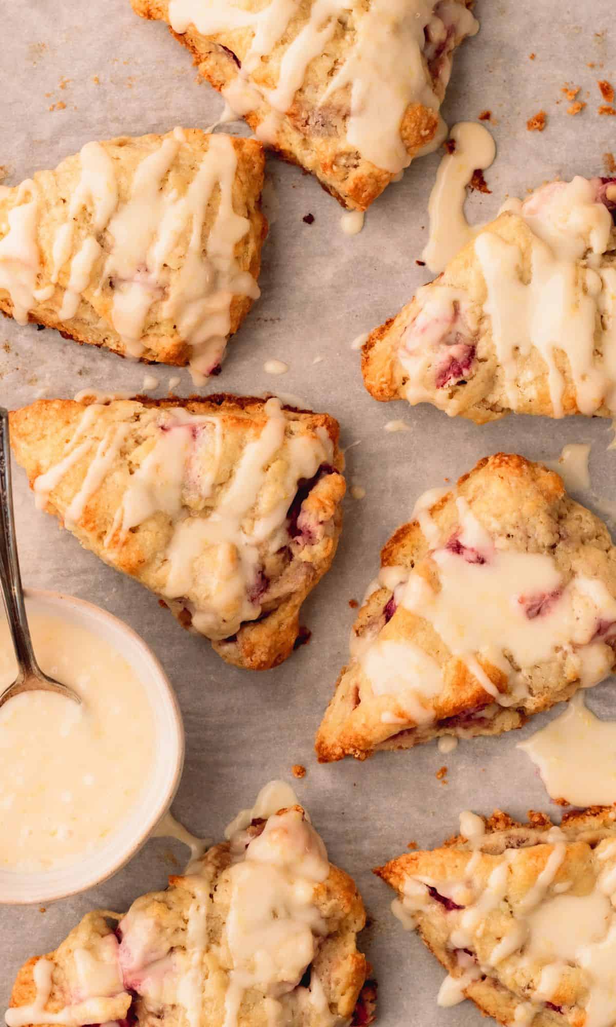 Several strawberry scones with lemon zest on a baking sheet.