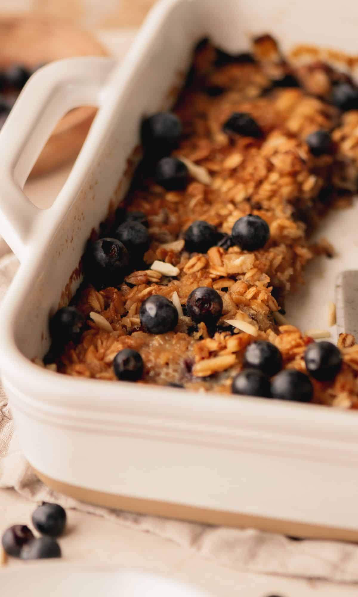 Banana blueberry baked oats in white baking dish with slices removed.