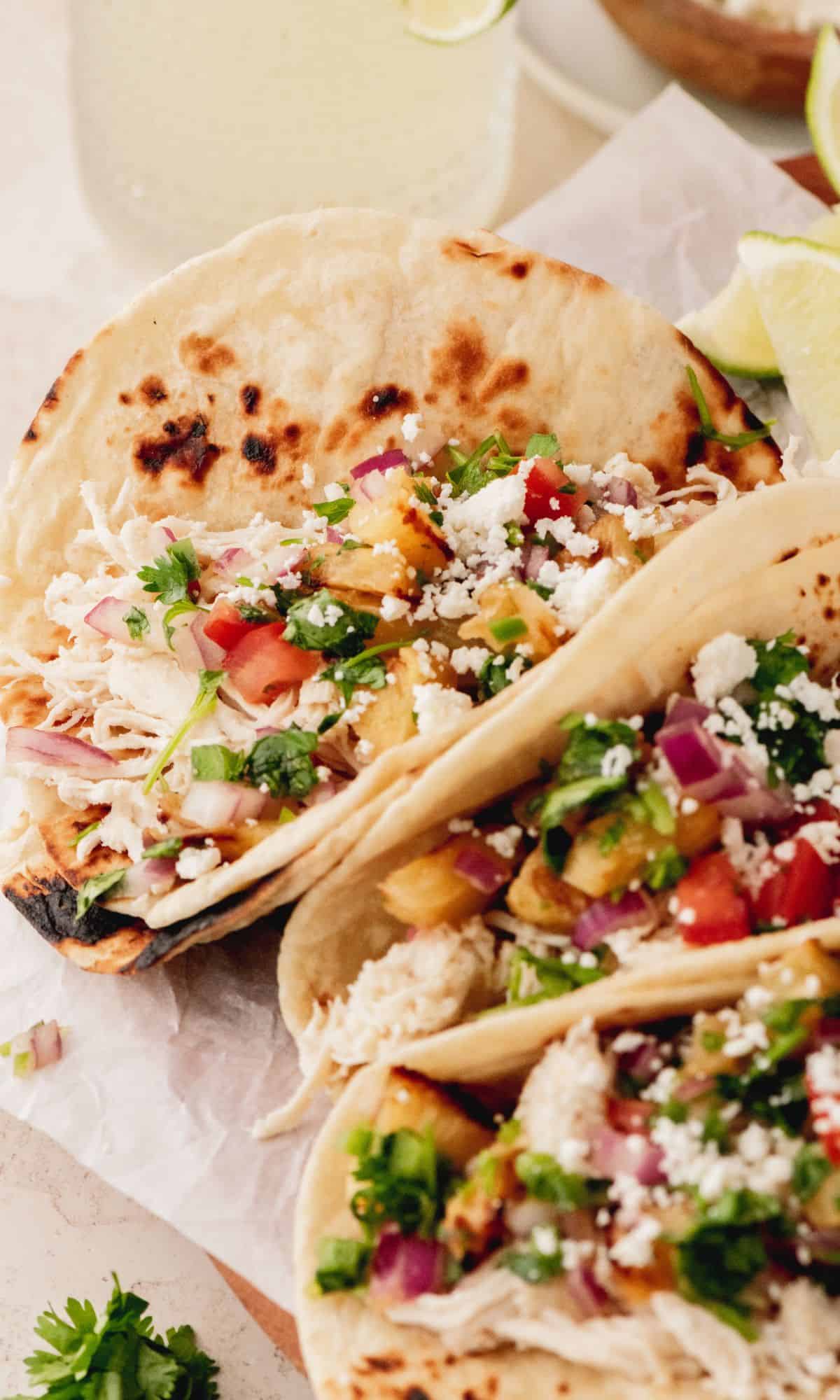 Three chicken tacos topped with pineapple salsa.