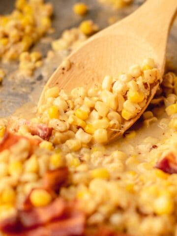 Skillet corn in the skillet with a wood spoon.