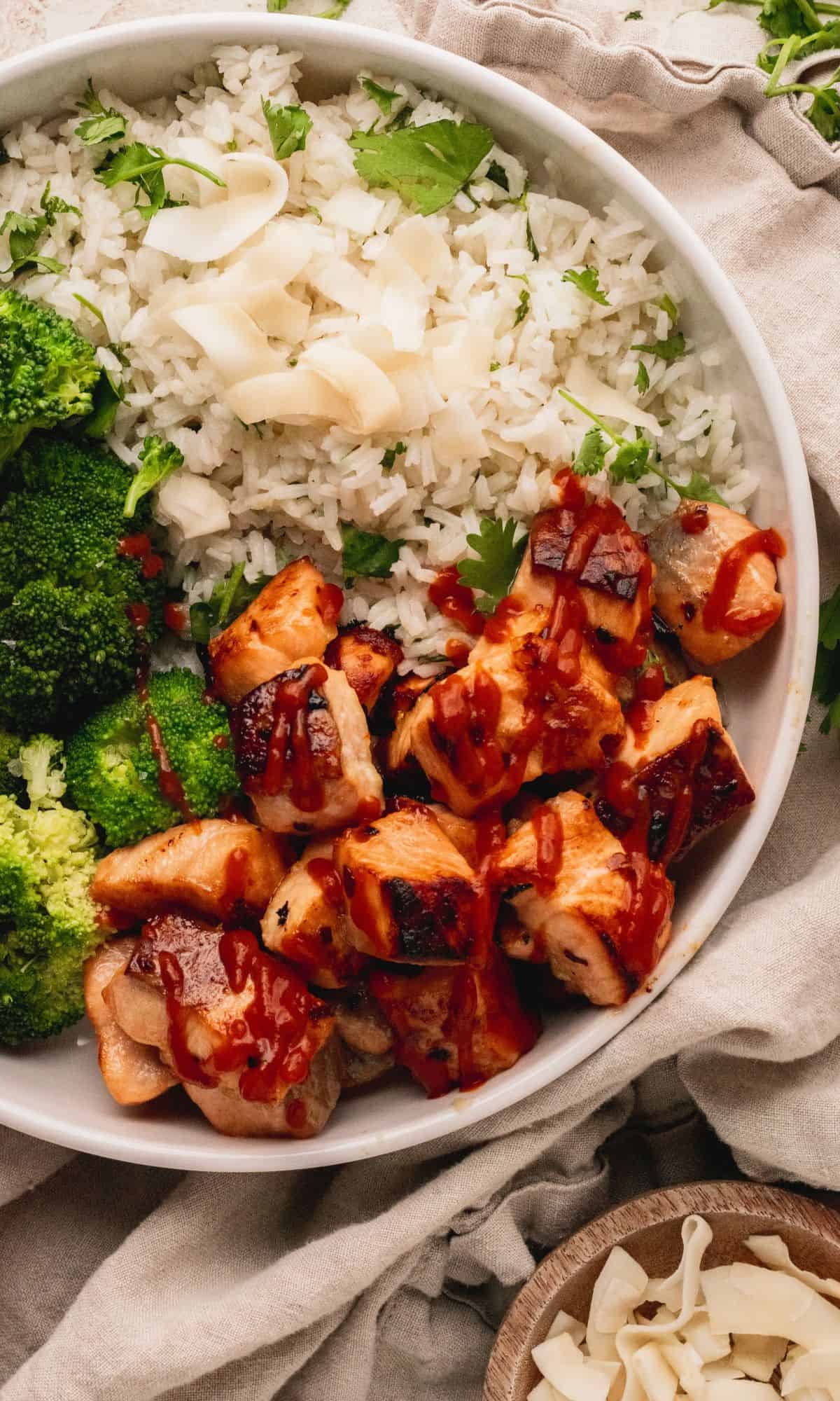 A white bowl with salmon bites, rice and broccoli.