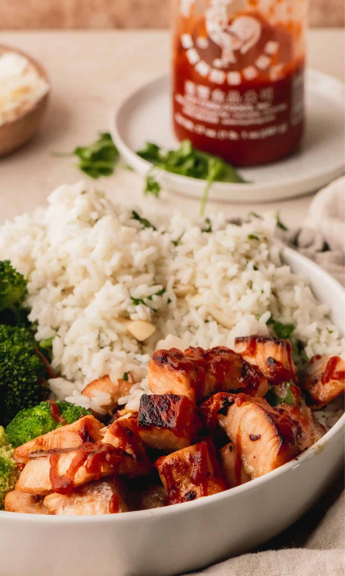 A white bowl with salmon bites, rice and broccoli.