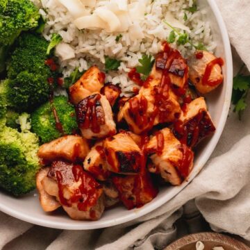 A bowl of salmon bites with rice and broccoli.
