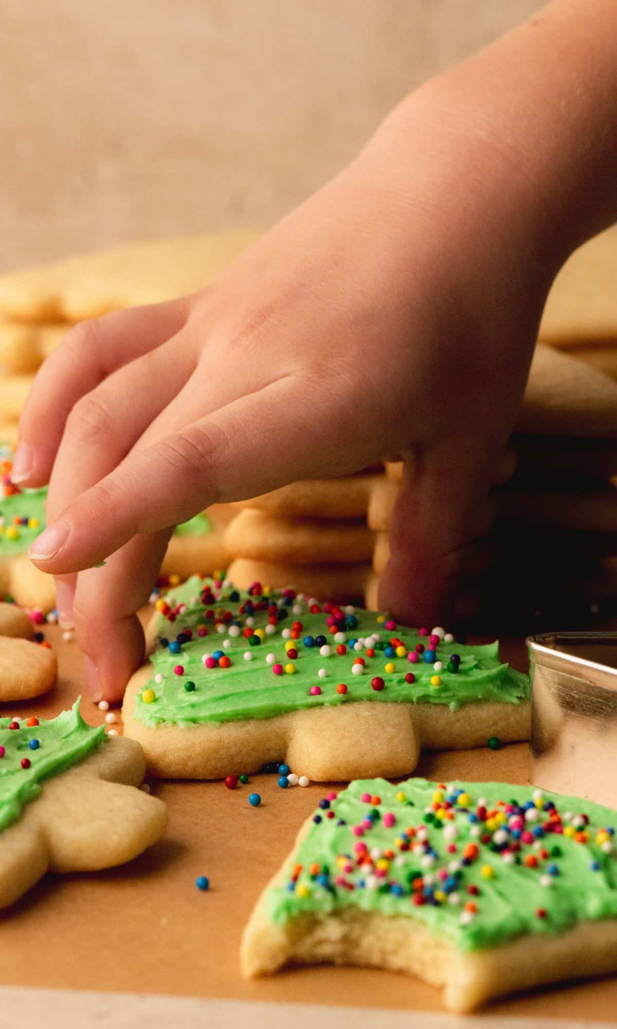 A hand grabbing a frosted frosted cookie.