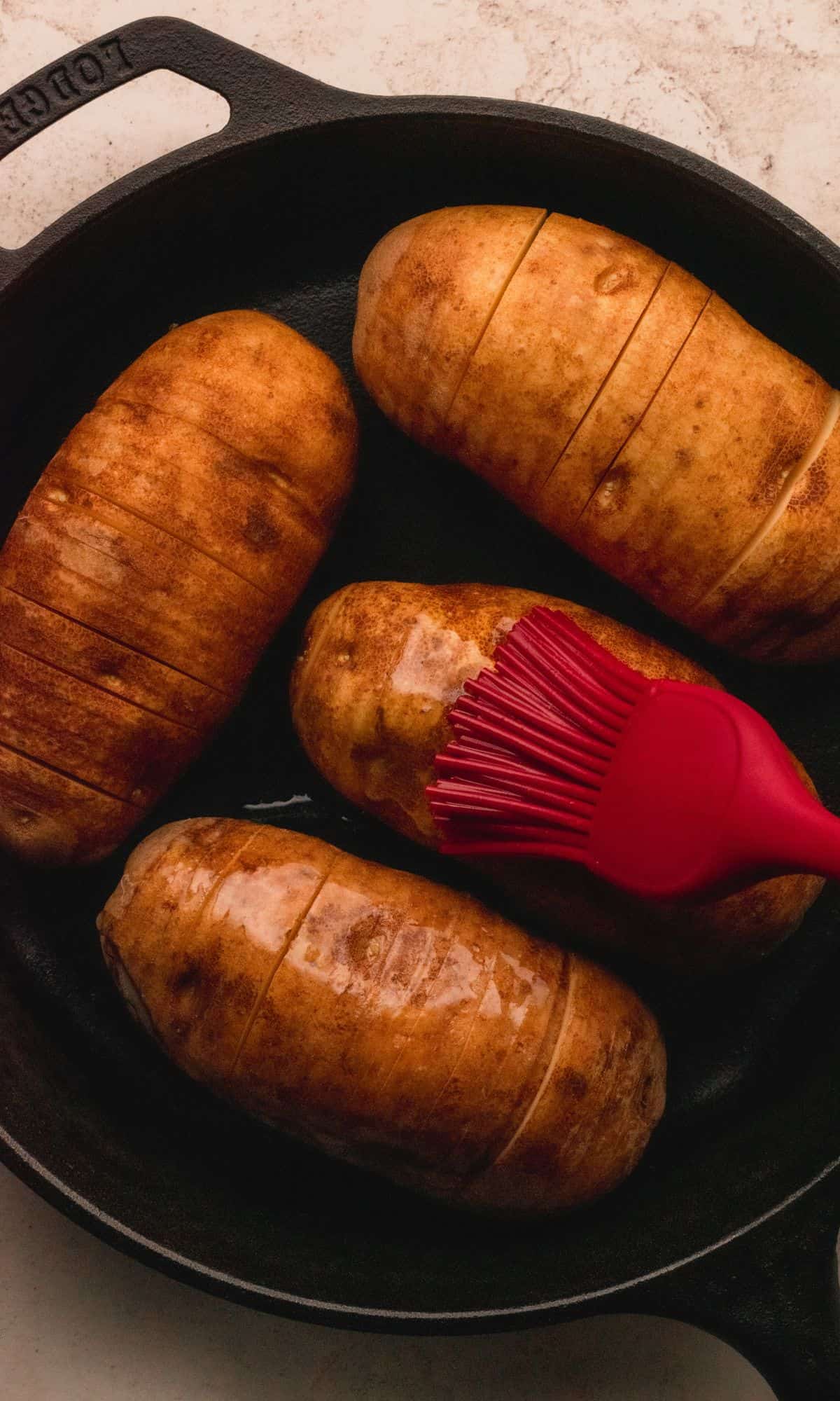 Brusing hasselback potatoes with melted butter.