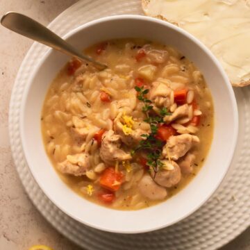 Soup in a white bowl with a slice of buttered bread next to it.